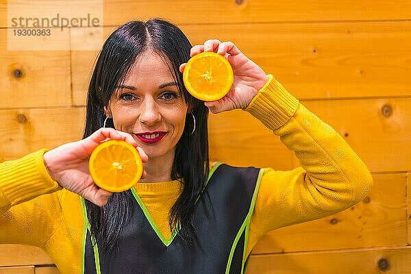 Spaß mit Orangen in der Hand eines brünetten kaukasischen Obstmädchens  das in einem Gemüseladen arbeitet