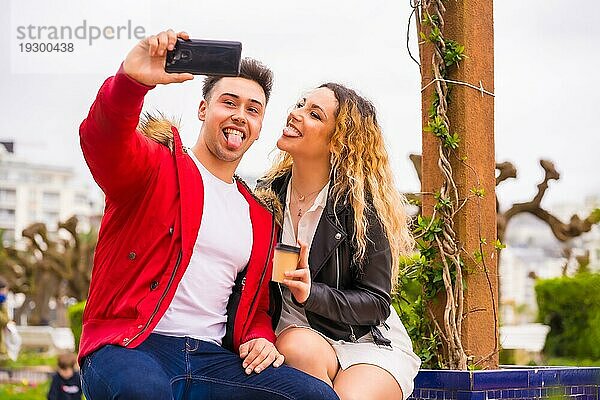 Lifestyle eines kaukasischen Paares beim Sightseeing im Urlaub  in einem Stadtpark  das lächelt und ein Foto mit dem Telefon macht
