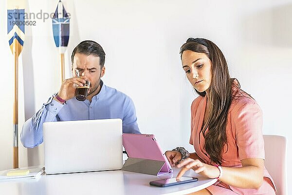 Ein Paar  das zu Hause telearbeitet  Schwierigkeiten der neuen Arbeitsnormalität  ein kaukasisches Paar  das an einem Tisch mit Computern im Wohnzimmer seines Hauses arbeitet