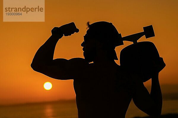 Silhouette eines durchtrainierten Mannes mit Bizeps vor dem Hintergrund eines hellen Sonnenuntergangs. Mittlere Aufnahme