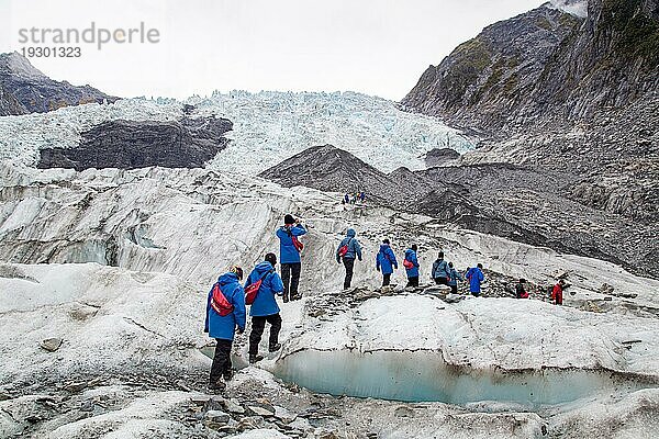 Franz Josef  Neuseeland  22. März 2015: Eine Gruppe von Touristen wandert auf dem Franz Josef Gletscher in Richtung eines Hubschraubers  Ozeanien