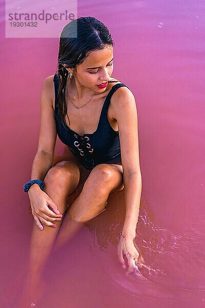 Posing einer jungen brünetten Kaukasierin im Sommerurlaub in der rosa Lagune von Torrevieja  die mit dem Wasser spielt  Alicante. Spanien