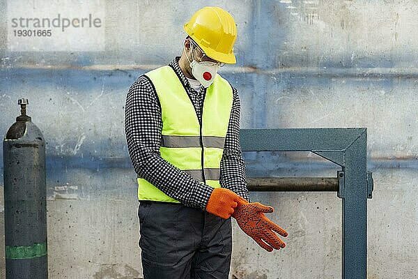 Frontansicht eines Arbeiters mit Schutzhelm und Schutzhandschuhen
