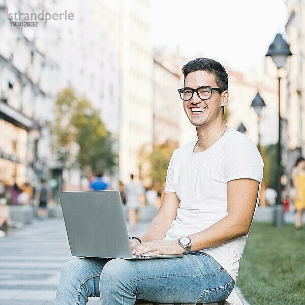 Porträt glücklicher junger Mann mit Laptop