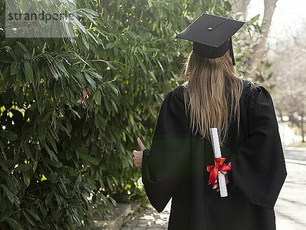 Rückenansicht Frau hält ihr Diplom