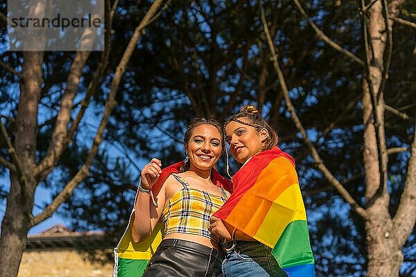 Eine Nahaufnahme von zwei jungen kaukasischen Frauen halten LGBT Stolz Flagge im Freien