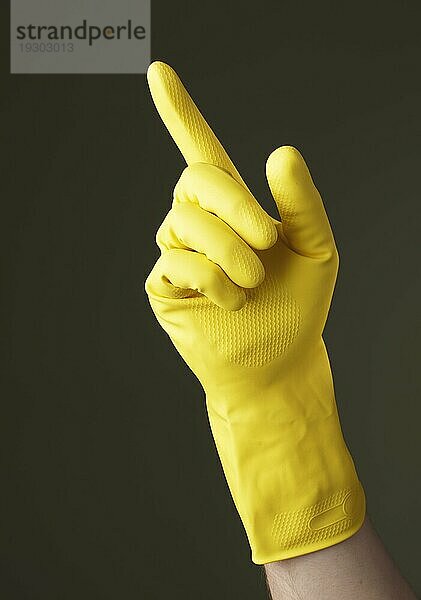 A Hand mit gelbem Schutzhandschuh  die mit einem Finger zeigt