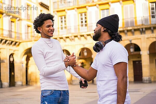 Lifestyle  zwei schwarze Latino Freunde winken  als sie sich auf der Straße treffen