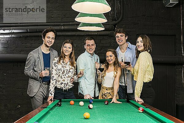Gruppe glücklich lächelnder Freunde mit Getränken am Snookertisch