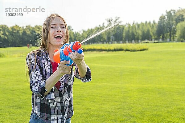 Medium shot fröhliches Mädchen spielt mit Wasserpistole