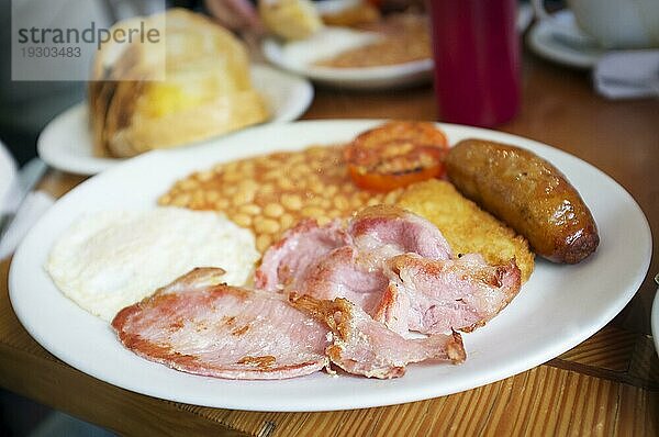 Traditionelles englisches Frühstück  Eier  Speck  Würstchen und Bohnen  serviert in einem Restaurant in London. Sehr kurze Tiefenschärfe