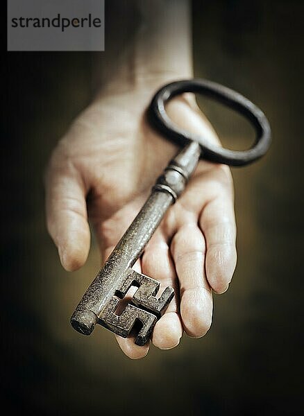 Mann hält großen antiken Schlüssel in der Hand. Sehr kurze Tiefenschärfe