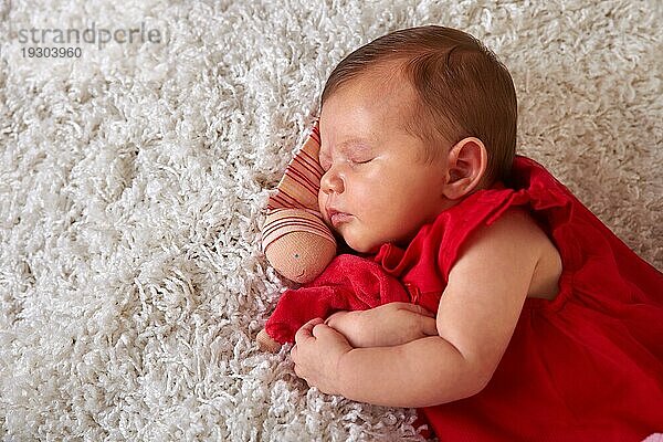 Schlafendes Neugeborenes im roten Kleid