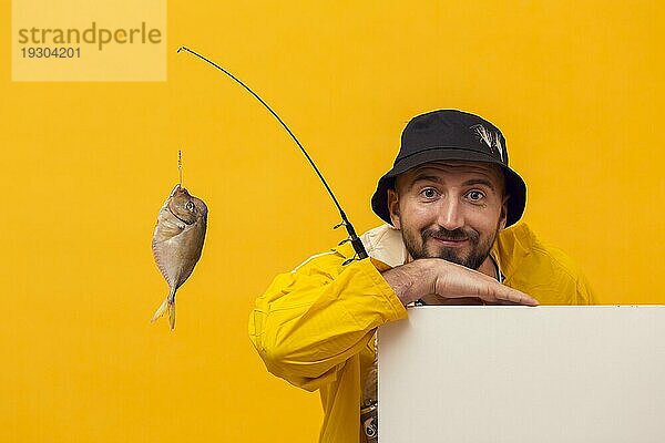 Vorderansicht Fischer posiert  während er eine Angelrute mit Fang hält
