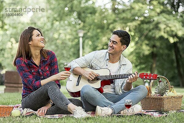 Ehepaar singt und spielt Gitarre im Park