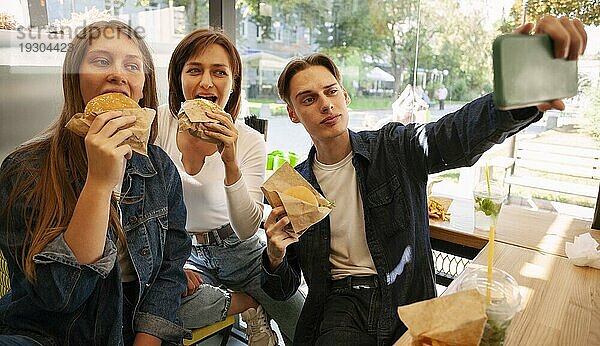 Gruppe von Freunden macht Selfie beim Essen von Fast Food