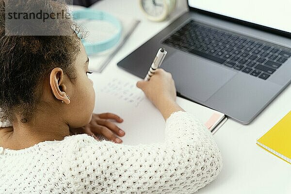 Kleines Mädchen besucht die Onlineschule zu Hause mit Laptop