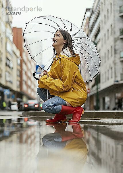 Frau mit Regenschirm stehend Regen Seitenansicht