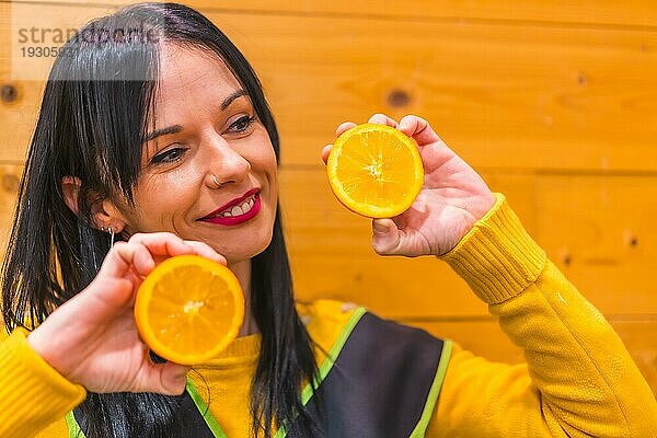 Spaß mit Orangen in der Hand eines brünetten kaukasischen Obstmädchens  das in einem Gemüseladen arbeitet