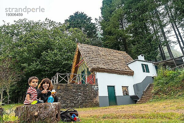 Eine Familie in einem traditionellen madeirensischen Haus wie dem von Santana im Wald von Caldeirao Verde  Santana