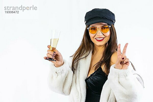 Junges brünettes Mädchen mit schwarzem Hut feiert Silvester auf einem weißen Hintergrund. Ich fordere das Modell mit einem sehr fröhlichen Glas Champagner heraus