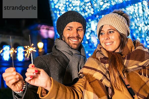 Winterporträt eines kaukasischen Paares  das die Weihnachtsbeleuchtung mit Fackeln in der Hand genießt  Lifestyle