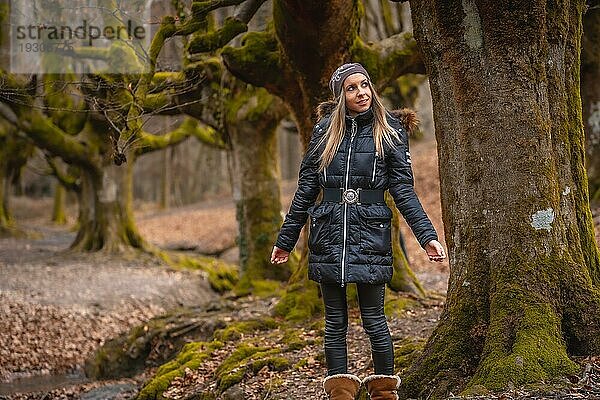 Eine glückliche junge Frau auf einem Baum im Wald von Otzarreta im Naturpark von Gorbea  Bizkaia. Baskenland. Lifestyle Session