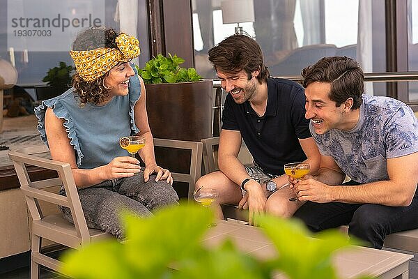 Drei stilvolle und junge erwachsene Freundinnen  die auf der Terrasse einer Bar Urlaub machen
