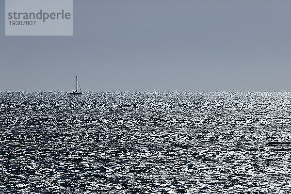 Segelboot am Horizont bei im Gegenlicht funkelnden und glitzernden Meer am Ärmelkanal kurz vor Sonnenuntergang  Portbail  Cotentin  Manche  Normandie  Frankreich  Europa