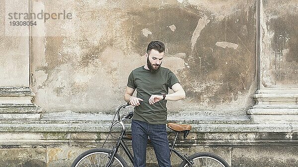 Mann mit seinem Fahrrad auf der Suche nach einer Uhr am Handgelenk