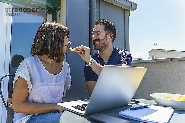 Ein Paar  das zu Hause eingesperrt ist  führt ein Videotelefonat mit einigen Freunden am Computer  die auf der Terrasse ihres Hauses vor einem weißen Hintergrund an einem Tisch sitzen. Klatschen bei dem Anruf