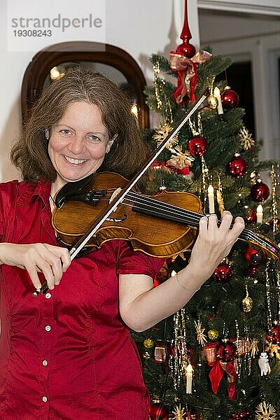 Frau musiziert auf einer Geige zu Weihnachten  woman is playing violin at christmas