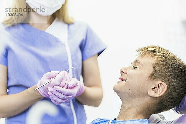 Lächelndes Kind Patientin vor weiblichen Zahnarzt hält Zahnsteinentferner