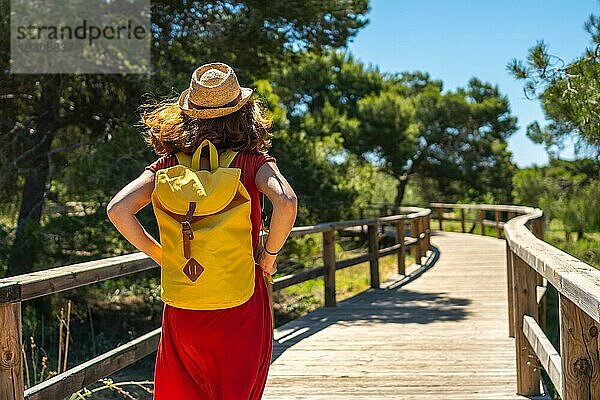 Eine junge Touristin  die auf dem Holzsteg zum Strand Moncayo in Guardamar del Segura  Alicante  spaziert. Gemeinschaft Valencia. Spanien