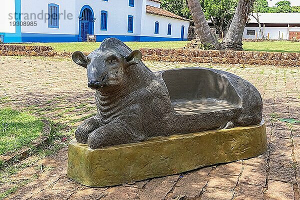 Ungewöhnliche Parkbank auf dem Platz eines brasilianischen Dorfes im Schatten von Bäumen  traditionelle Häuser im Hintergrund