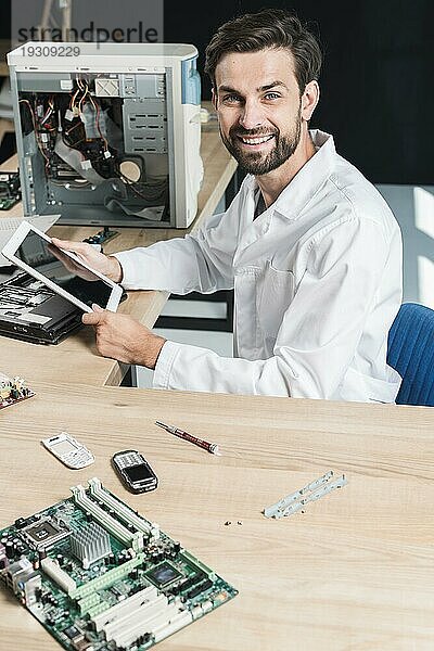 Portrait lächelnder junger männlicher Techniker mit digitalem Tablet