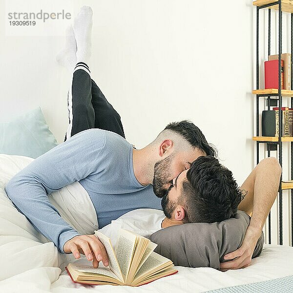Mann küsst seinen Freund liegenden Bett mit le s lehnte Wand