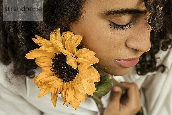 Attraktive ethnische weinende Frau mit Blume