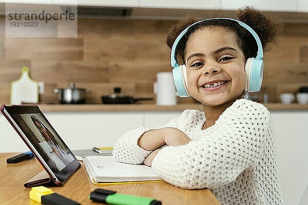 Seitenansicht Smiley kleines Mädchen während Onlineschule mit Tablet Kopfhörer