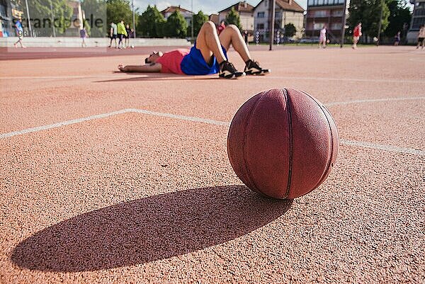 Basketballspieler am Boden mit Ball im Vordergrund
