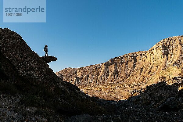 Silhouette einer jungen Frau beim Klettern auf einem Stein in der Wüste von Tabernas  Provinz Almería  Andalusien. Eine Wanderung auf der Rambla Las Salinas