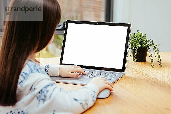 Ein junges Mädchen nutzt einen Computer im Fernunterricht für ihre Schularbeiten