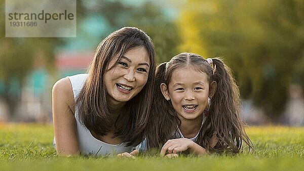 Vorderansicht asiatische Mutter Tochter bleiben Gras zusammen
