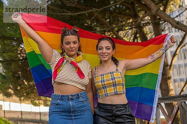 Eine Nahaufnahme von zwei jungen kaukasischen Frauen halten hoch LGBT Stolz Flagge im Freien