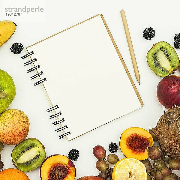 Draufsicht Spirale Notizblock Bleistift verschiedene Früchte weißer Hintergrund