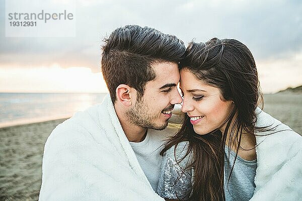 Verliebtes Paar am Strand  bedeckt mit einer weißen Decke