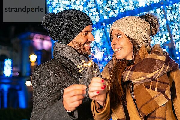 Winterporträt eines kaukasischen Paares  das die Weihnachtsbeleuchtung mit Fackeln in der Hand genießt  Lifestyle