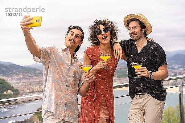 Glückliche Freunde machen ein Selfie bei einer Dachparty mit Meerblick im Urlaub