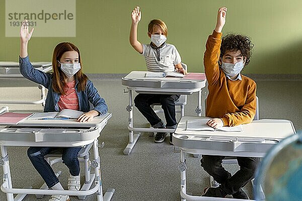 Frontansicht Kinder mit medizinischen Masken Schule heben ihre Hände
