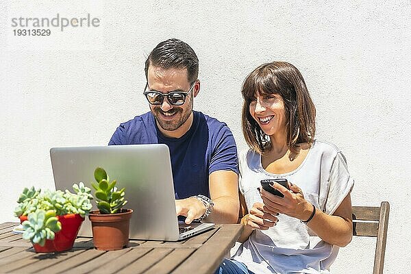 Ein Ehepaar  das zu Hause mit dem Computer einen Videoanruf mit Freunden führt